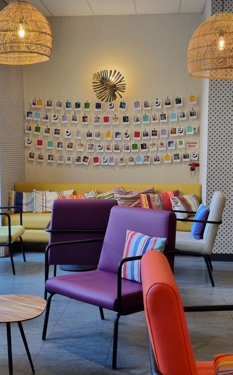 Zona común del Hotel Ibis Styles Perpignan con sofás coloridos y cojines de rayas catalanas