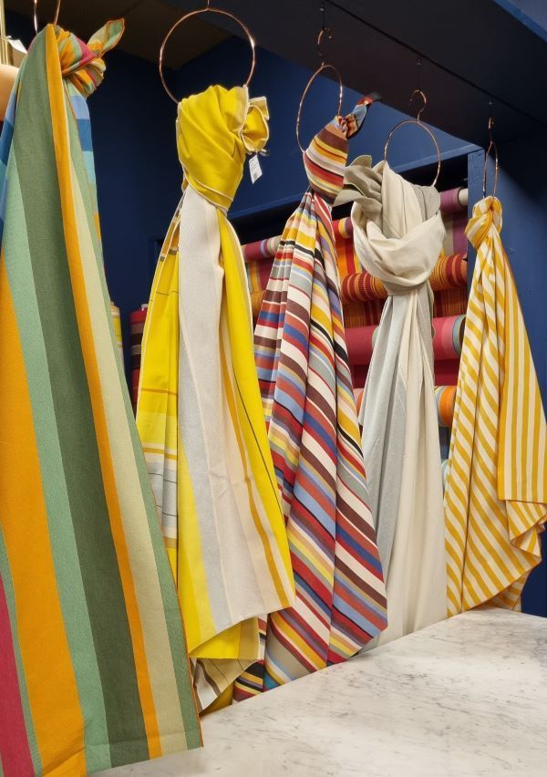 Interior de Les Toiles du Soleil con telas colgadas con rayas de colores en Perpignan
