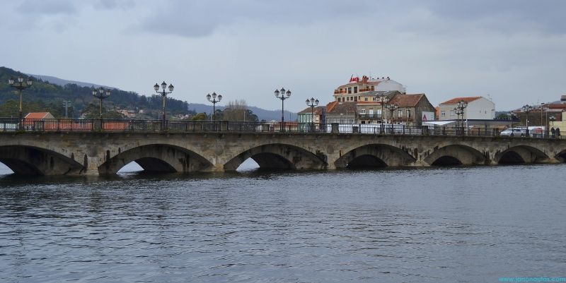 Vista del Puente del Burgo sobre el río Lérez, con reflejos en el agua y el casco antiguo de Pontevedra al fondo.