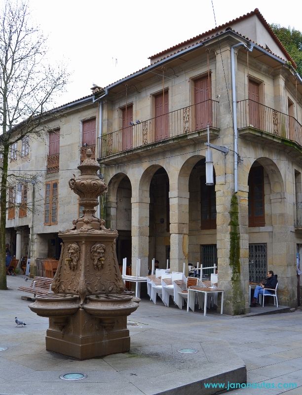 Fuente tradicional en la Praza da Verdura de Pontevedra, rodeada por los soportales y edificios históricos.