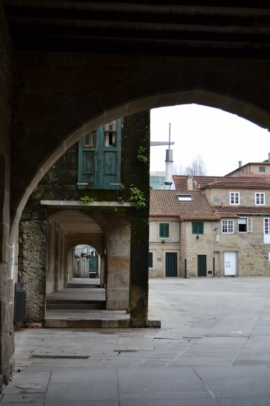 Vista del arco de entrada a la Praza da Pedreira en Pontevedra, con los soportales y edificios históricos que rodean la plaza.