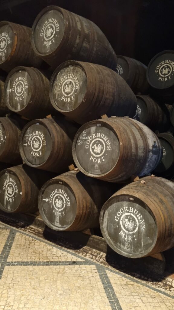 Barricas de roble apiladas con el logo de Cockburn's Port en la galería de envejecimiento de Oporto
