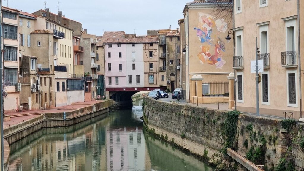 Canal de la Robine a su paso por el centro histórico de Narbonne con mural en fachada