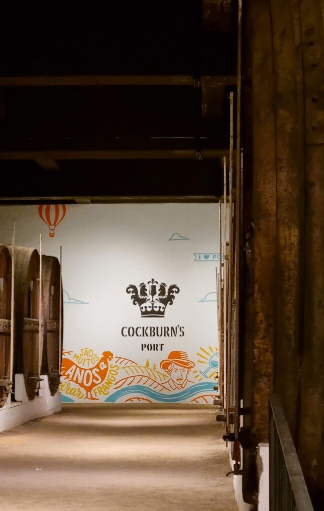 Mural decorativo de Cockburn's Port al fondo de una galería de barricas en las Bodegas Cockburn's de Oporto