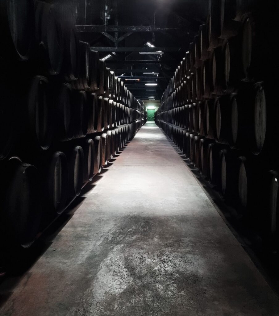 Pasillo entre barricas apiladas en la galería de envejecimiento de las Bodegas Cockburn's de Oporto