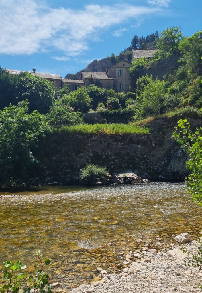 Casas de piedra de Sainte-Énimie junto al río Tarn con orilla de cantos rodados, Lozère