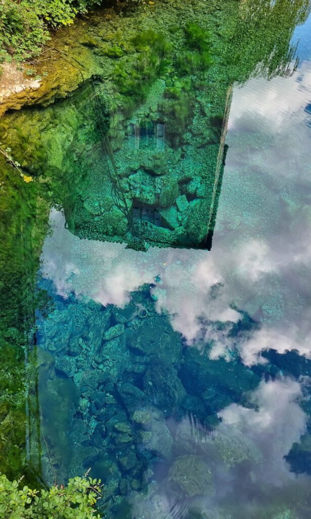 Reflejo de la torre y el cielo sobre las aguas turquesas de la Source de la Burle en Sainte-Énimie